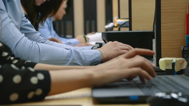Many hands are typing on a laptop