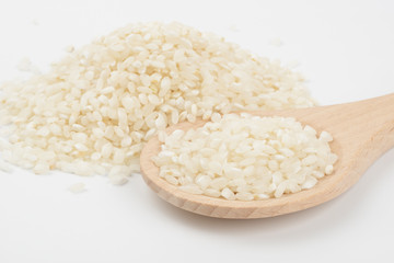 Arroz redondo blanco en una cuchara de madera sobre fondo blanco