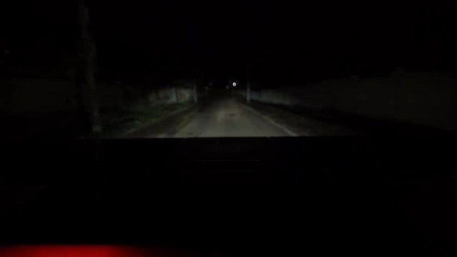 POV driving police car with blue red emergency lights flashing at night on the street. LED warning lighting mounted on the roof of police vehicle.