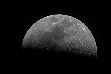 Horizontal big and bright Moon in its first quarter phase, isolated in dark background into space, taken by telescope.