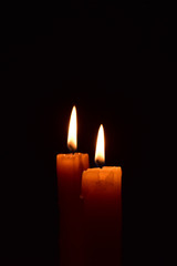 Yellow light candle burning brightly in the black background.