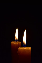 Yellow light candle burning brightly in the black background.