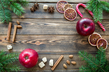 Colorful Christmas background. Traditional spices, dried orange slices and red apples on brown wooden table. Space for greeting.
