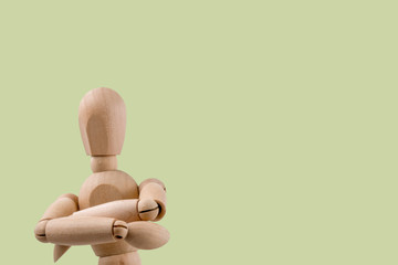 Wooden dummy holds two hands crossed in judgemental pose light green background