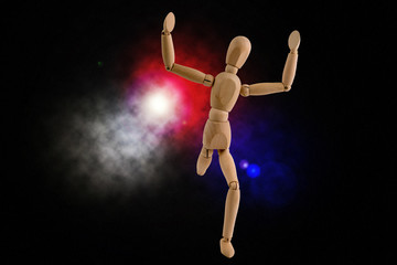 Wooden dummy running holding hands in air on black background with red blue and white lights....