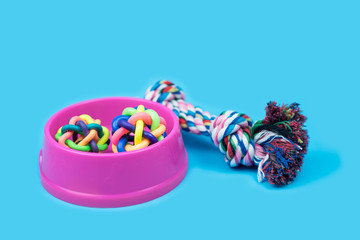 Pet accessories concept. Pet bowl, Rope and rubber ball on light blue background.