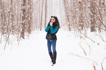 Young pretty woman walking in the winter snowy park at sunny day