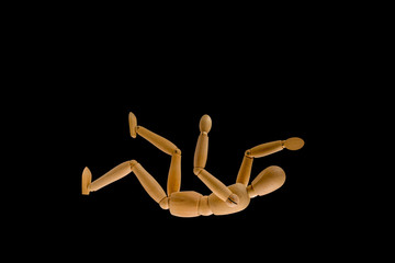 Wooden dummy falls in the dark on black background