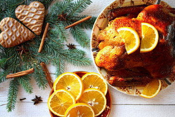 Fototapeta Pieczona kaczka z pomarańczami otoczona gałązkami świerku, piernikami i gwiazdkami anyżu, świąteczny obiad w Boże Narodzenie obraz