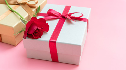 Red rose and gift box on a pink background.