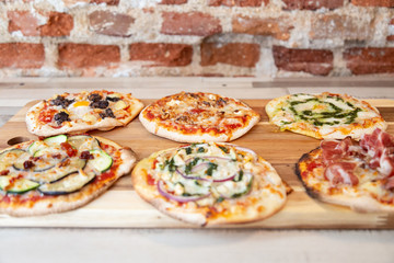 Aerial view of six different pizzas on a wooden board