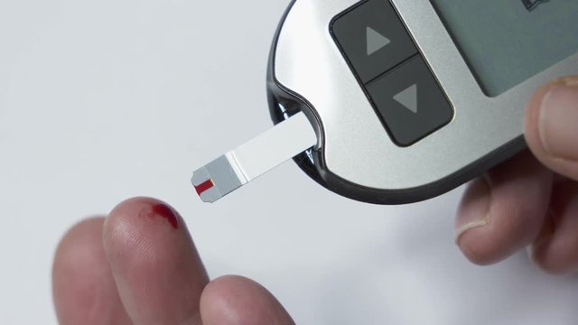 Patient with diabetes using a blood glucose meter to test blood glucose