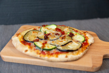 Close up of a pizza with zucchini, eggplant and dry tomatoes with gratin mozzarella cheese