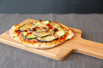 Pizza with zucchini, eggplant and dry tomatoes with gratin mozzarella cheese