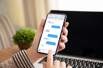 female hand holding phone with app messenger on the screen