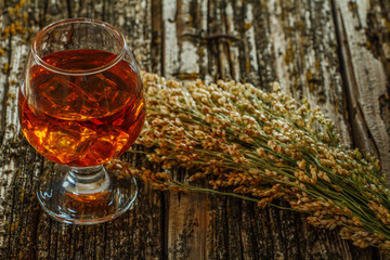 Whiskey with ice or brandy in a glass and a square carafe on an old wooden background. Whiskey with...