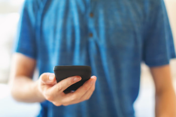 Young man using his smartphone in a bright interior room