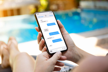 woman by the pool holding phone with app messenger - obrazy, fototapety, plakaty