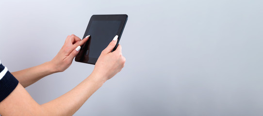 Young woman with a tablet computer on a gray background