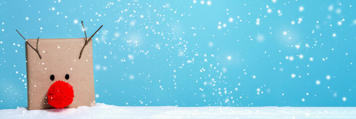 Pompom reindeer gift box in a snow covered landscape