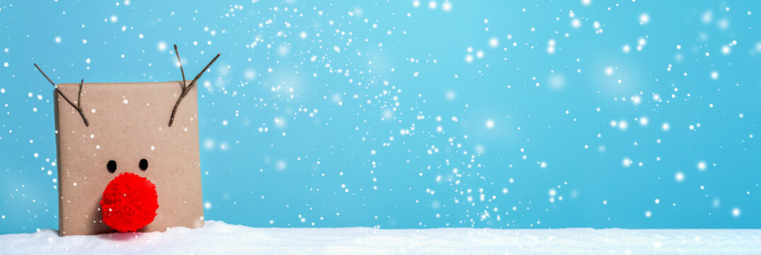 Pompom reindeer gift box in a snow covered landscape