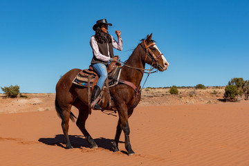 young native american woman riding horse in the desert