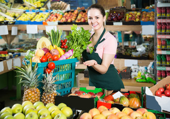 salesgirl in store with basket filled with fresh fruits and vegetables