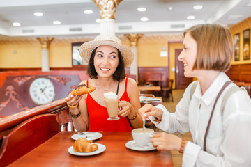 Two girl friends drinking coffee in the cafe and talking. Friendship concept