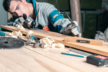 Man in overalls planing a tree in the Studio with a hand planer