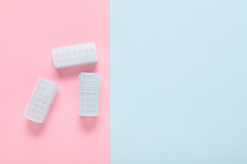 hair curlers on blue and pink paper background