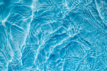 Background of rippled pattern of clean water in a blue swimming pool