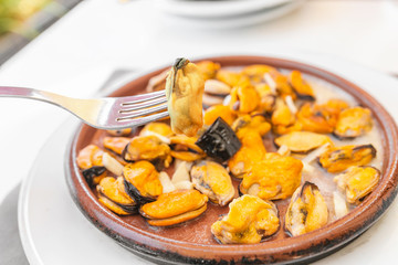 Woman eating shellfish mussels in seafood restaurant