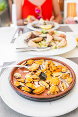Woman eating shellfish mussels in seafood restaurant