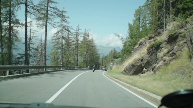 traveling by car on the mountain roads of the Simplon pass connecting Italy and Switzerland. Super slow motion 240 fps. motorcycles and cars and in the background mountains and sky
