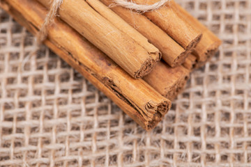 Cinnamon sticks tied with jute rope on burlap background