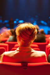 Jeune femme blondede dos assise dans salle de spectacle