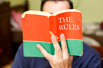person holding and reading book with title text the rules