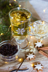 Glass with white bright mulled wine with raisins and almonds as hot drink for the festive season. Selective focus.