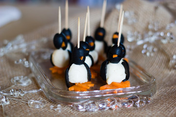 Healthy fun art food snacks as appetizers or for children in the shape of penguins with carrots, mozzarella cheese and olives