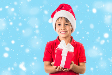Child boy in christmas Santa hat and red present box on white.