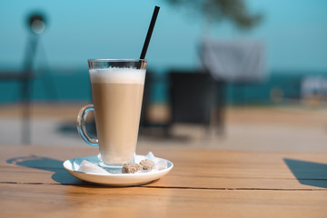 Latte mug with black drinking straw on wooden table