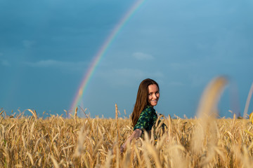 Fototapeta na wymiar Portrait of a young woman in a field with wheat ears on a rainbow background