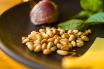 Fresh ingredients for preparing Italian pesto sauce - lemon basil sprigs, peeled seeds of cedar nuts, large garlic clove, Greek olive oil, Parmesan cheese