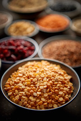 Raw peas halfs seeds in ceramic bowl. Composition of superfoods in background. Placed on dark rusty table. Selective focus.