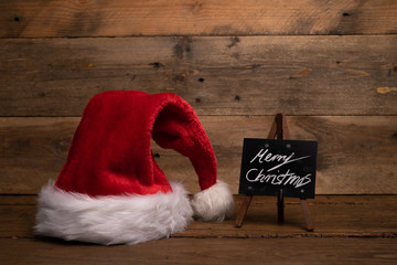 Obraz na płótnie Canvas Still life Weihnachtsmütze mit Kreideltafel Schrift Merry Christmas auf Holz Botschaft vintage