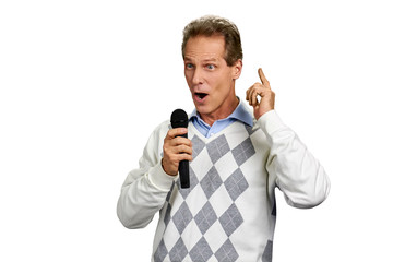 Man talking into microphone on white background. Middle-aged caucasian man holding microphone and gesticulating on white background.