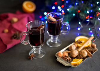 Red mulled wine in glasses with electric lights at dark background