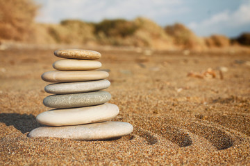 Fototapeta na wymiar Stones pyramid balance on sand and blurred background. Spa therapy theme. Sea view. Beach. Zen garden.