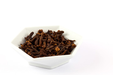 Spice cloves in a small white ceramic dish isolated on white background