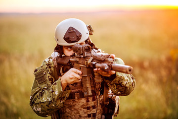 portrait of young soldier face with camouflage against a sunset background